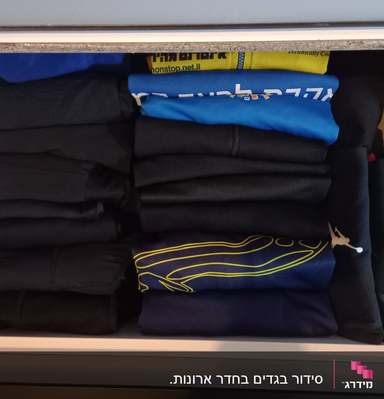 מגירת בגדים מסודרת עם חולצות מקופלות בצבעים שונים